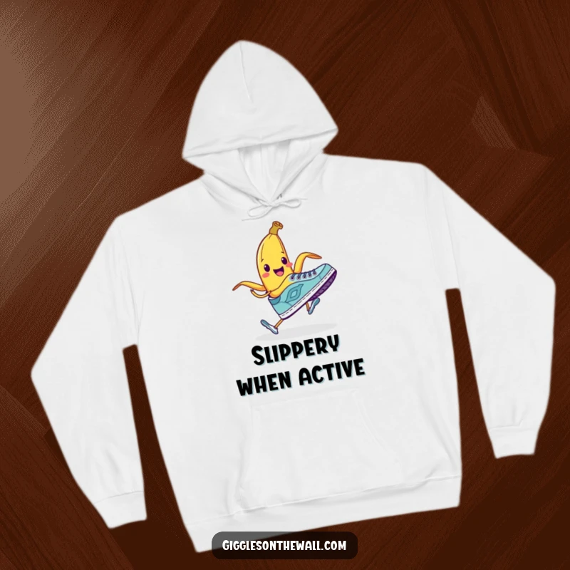 Funny hoodie showcasing a smiling banana peel ready to trip a running shoe, offering comfort and comedic charm.