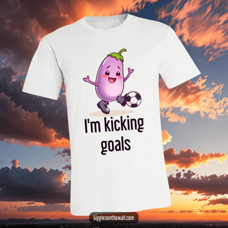 Funny T-shirt featuring a smiling eggplant wearing boots, enthusiastically kicking a football with comedic flair.